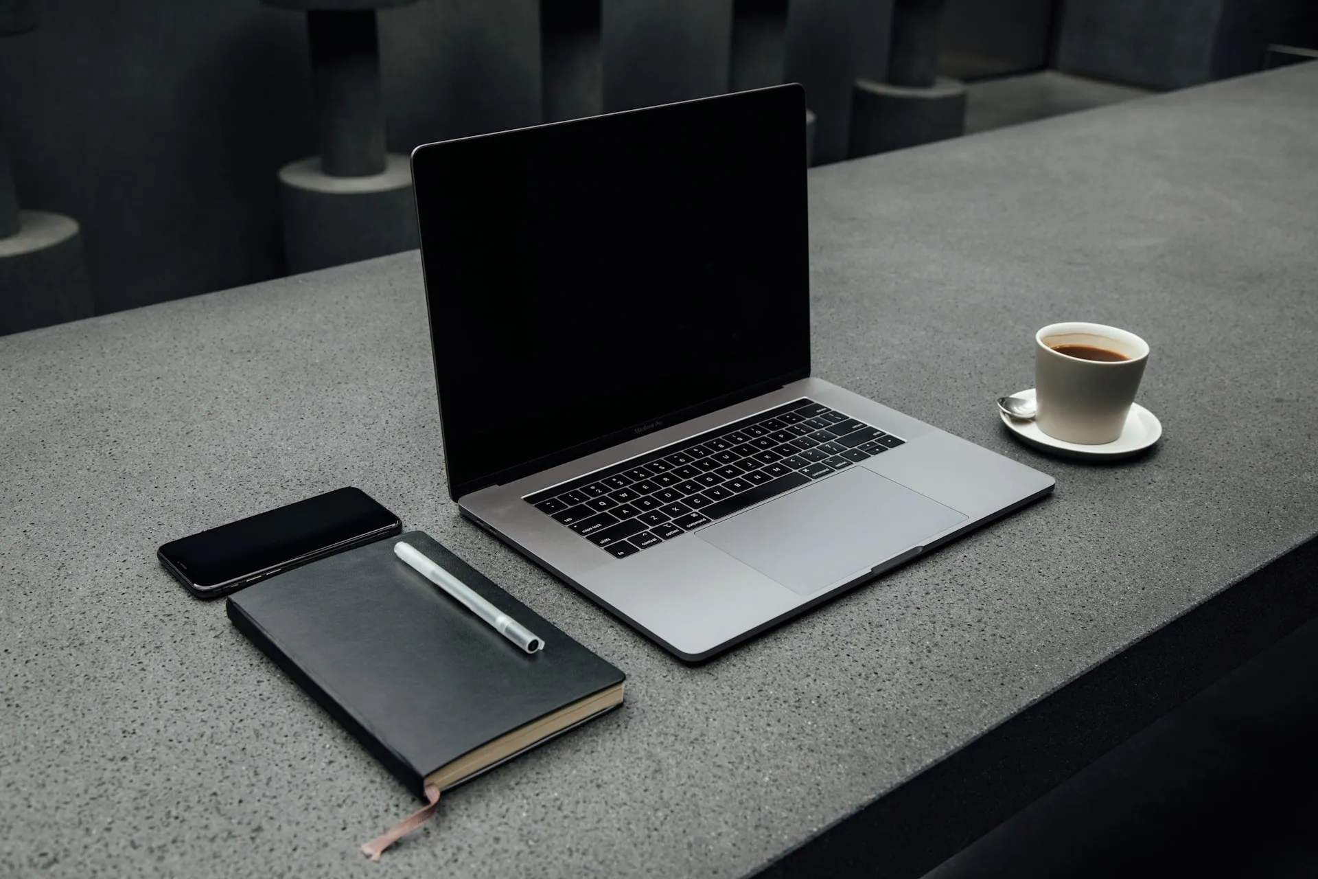 Laptop and notebook on a dark desk
